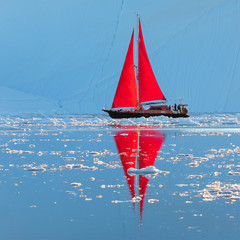 Wall Mural - beautiful red sailboat in the arctic next to a massive iceberg showing the scale. ilulissat, disko b