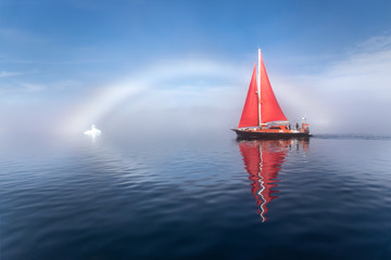 Wall Mural - beautiful red sailboat under a rainbow - fog bow on a foggy day lighted by sunlight. disko bay, gree