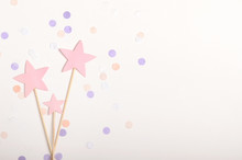 Pink Stars On Stick Topping On White Background With Confetti, Pastel Colors. Children's Holiday, New Year. Top View, Flat Lay, Copy Space.