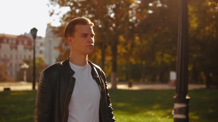 Poster - portrait young businessman walking on the street. handsome caucasian guy wearing trendy casual jacket outdoors slow motion
