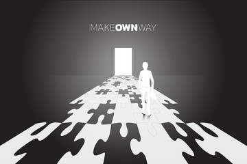 Poster - Silhouette of businessman with briefcase standing on road to the door from jigsaw piece. business concept of make you own way. 