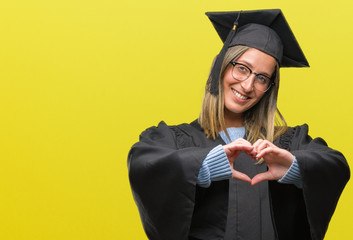 Poster - Young beautiful woman wearing graduated uniform over isolated background smiling in love showing heart symbol and shape with hands. Romantic concept.