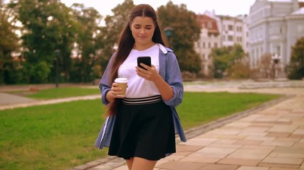 Leinwandbilder - businesswoman messaging on mobile on the run young woman drinking coffee to go using smartphone walking on the street.
