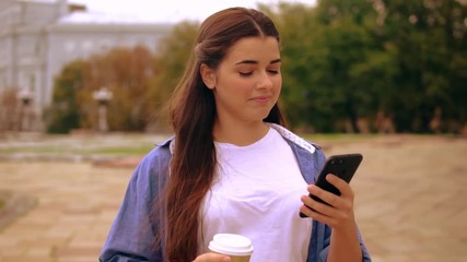Poster - caucasian woman messaging on mobile on the run drinking coffee to go using smartphone walking on the street.