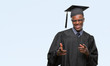 © Krakenimages.com - Young graduated african american man over isolated background pointing fingers to camera with happy and funny face. Good energy and vibes.