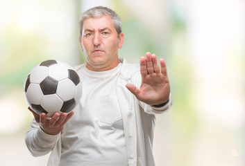 Canvas Print - Handsome senior man holding soccer football ball over isolated background with open hand doing stop sign with serious and confident expression, defense gesture