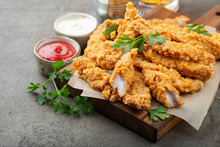Breaded Chicken Strips With Two Kinds Of Sauces On A Wooden Board. Fast Food On Dark Brown Background