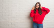 © Krakenimages.com - Young brunette woman standing over white brick wall smiling confident showing and pointing with fingers teeth and mouth. Health concept.