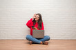© Krakenimages.com - Young brunette woman sitting on the floor using laptop and smartphone with happy face smiling doing ok sign with hand on eye looking through fingers