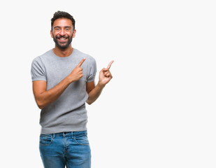 Wall Mural - Adult hispanic man over isolated background smiling and looking at the camera pointing with two hands and fingers to the side.