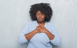 © Krakenimages.com - Young african american woman over grey grunge wall wearing winter sweater smiling with hands on chest with closed eyes and grateful gesture on face. Health concept.