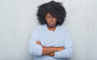 Sticker - Young african american woman over grey grunge wall wearing winter sweater skeptic and nervous, disapproving expression on face with crossed arms. Negative person.