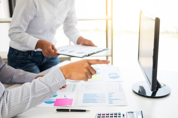 Wall Mural - businessman working together pointing screen while discussing explaining a business analysis displayed on the monitor desktop PC with colleagues in the interior of a modern office.