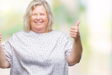 Senior plus size caucasian woman over isolated background success sign doing positive gesture with hand, thumbs up smiling and happy. Looking at the camera with cheerful expression, winner gesture.