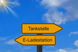 © studio v-zwoelf - Zwei Schilder weisen auf eine Tankstelle und Ladestation für Elektro Autos