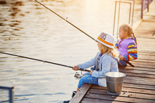 Little Girls Fishing On The Lake, Sitting On A Wooden Pontoon