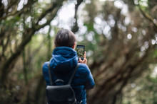 Young traveler woman taking a photo of forest landscape in Anaga Country Park