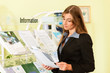© Kzenon - Young businesswoman standing in front of rack reading information leaflet