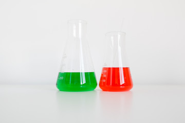 Two erlenmeyer flasks on white laboratory table