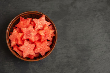 Wall Mural - Watermelon slices in the shape of a star in bowl on a black plate. Top view, with copy space