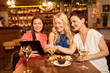 © Syda Productions - leisure, technology and lifestyle concept - happy women with tablet pc computer at wine bar or restaurant