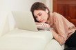 © feeling lucky - young woman listen to music from computer and fall asleep on sofa in living room