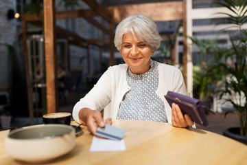 Sticker - old age, leisure, payment and finances concept - happy senior woman with credit card and wallet paying bill for coffee and dessert at street cafe