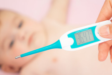 Baby sick with measuring electric thermometer. Child fever ill. Kid catch cold with temperature. Sick child in bed with fever measuring temperature with medical thermometer.