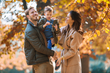 Wall Mural - Young family having fun in the autumn park with his son.