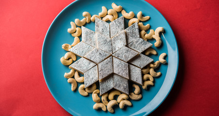 Kaju Katli is a Diamond shape Indian sweet made using cashew sugar and mava, served in a plate or bowl over moody background. selective focus