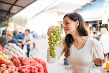 Young Woman Buying Fresh Grapes On The Market.