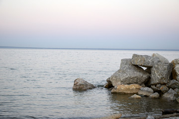 The sandy shore of the lake and stony places of the coast, at sunset. The picture was taken on a warm summer evening.