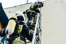 Selective Focus Of Firefighters In Fireproof Uniform Standing On Ladder