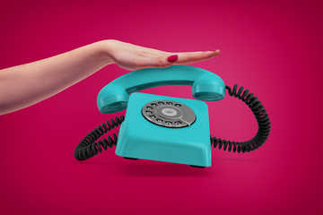 Wall Mural - an elegant female hand presses down a handle of a retro blue rotary phone that rings and almost jump