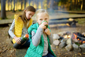 Wall Mural - cute preteen girl drinking tea and roasting marshmallows on stick at bonfire. child having fun at ca