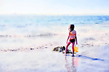 Watercolour Painting. Back View Of Young Girl Holding An Orange Bucket On A Sandy Beach In Summer, Looking Out To Sea.