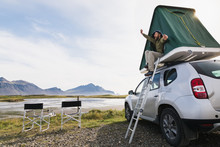 Young Bearded Man Sitting And Stretching In A Roof Top Tent Mounted On Offroad Car In Hofn Camping Site, Iceland
