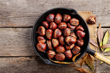 Roasted Chestnuts In A Pan On A Wooden Background. Top Wiev.
