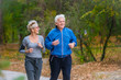 © lordn - Smiling senior active couple jogging together in the park