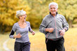 © lordn - Smiling senior active couple jogging together in the park