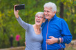© lordn - Smiling senior couple in the park taking selfie