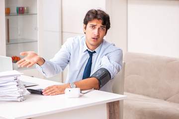 Man under stress measuring his blood pressure