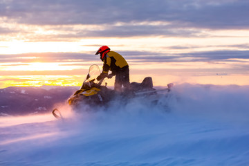 Wall Mural - A man is ridind snowmobile in mountains.