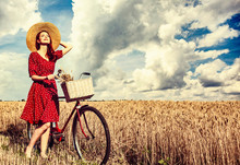Redhead Girl With Bicycle On Wheat Field.