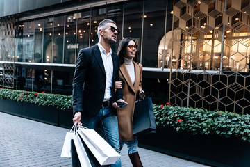 Wall Mural - Shopping. Black Friday. Couple. Love. Man and woman with shopping bags are talking and smiling while walking down the street