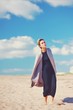 © raisondtre - Fashion. Portrait of young beautiful modern woman outdoors. Slim figure, black dress, light grey coat, a stylish haircut, sandy beach, blue sky.