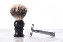 A Mens Razor And Shaving Brush On A Wet Bathroom Counter Top