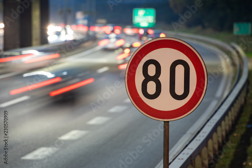 Fotografía Long exposure shot of traffic sign showing 80 km/h speed limit on a highway full