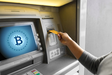 Wall Mural - finance, cryptocurrency and technology concept - close up of woman hand inserting bank card to atm machine with bitcoin icon on screen