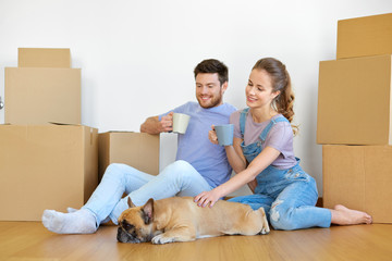 Poster - mortgage, people and real estate concept - happy couple with boxes and french bulldog dog moving to new home and drinking coffee